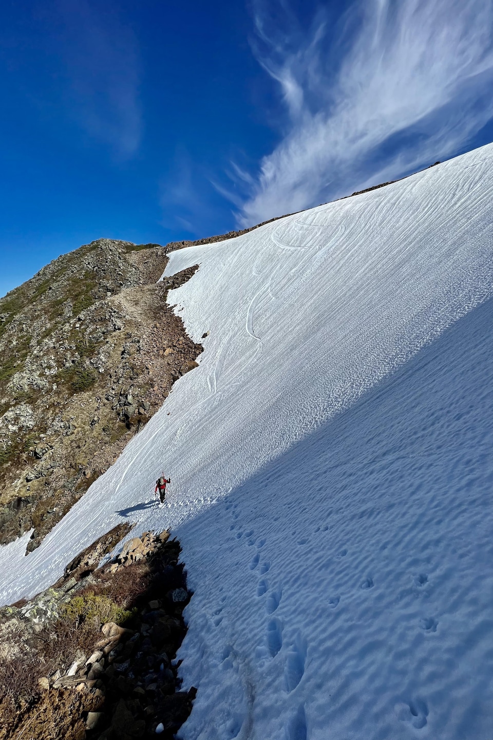 Au loin, un skieur alpin sur une montagne partiellement enneigée.