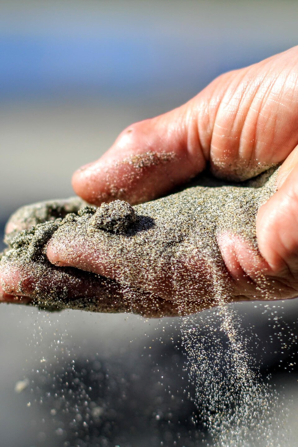 Une main avec du sable qui s'écoule entre les doigts.