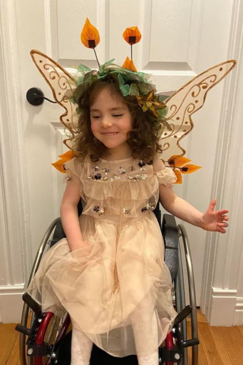 Brenna déguisée en papillon et assise dans une chaise roulante.