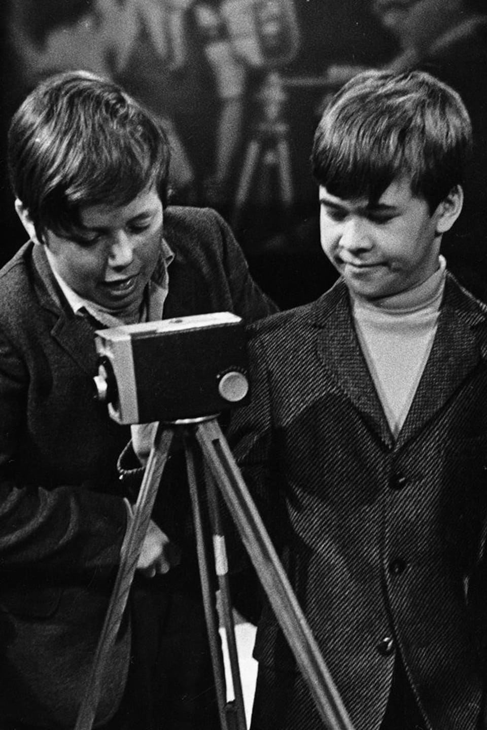 Quatre garçons s’amusent avec une caméra et des accessoires sous le regard de Claude Jasmin.
