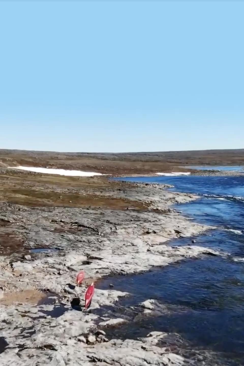Capture d'écran d'une vidéo de deux personnes faisant du portage de canot en bordure d'une rivière
