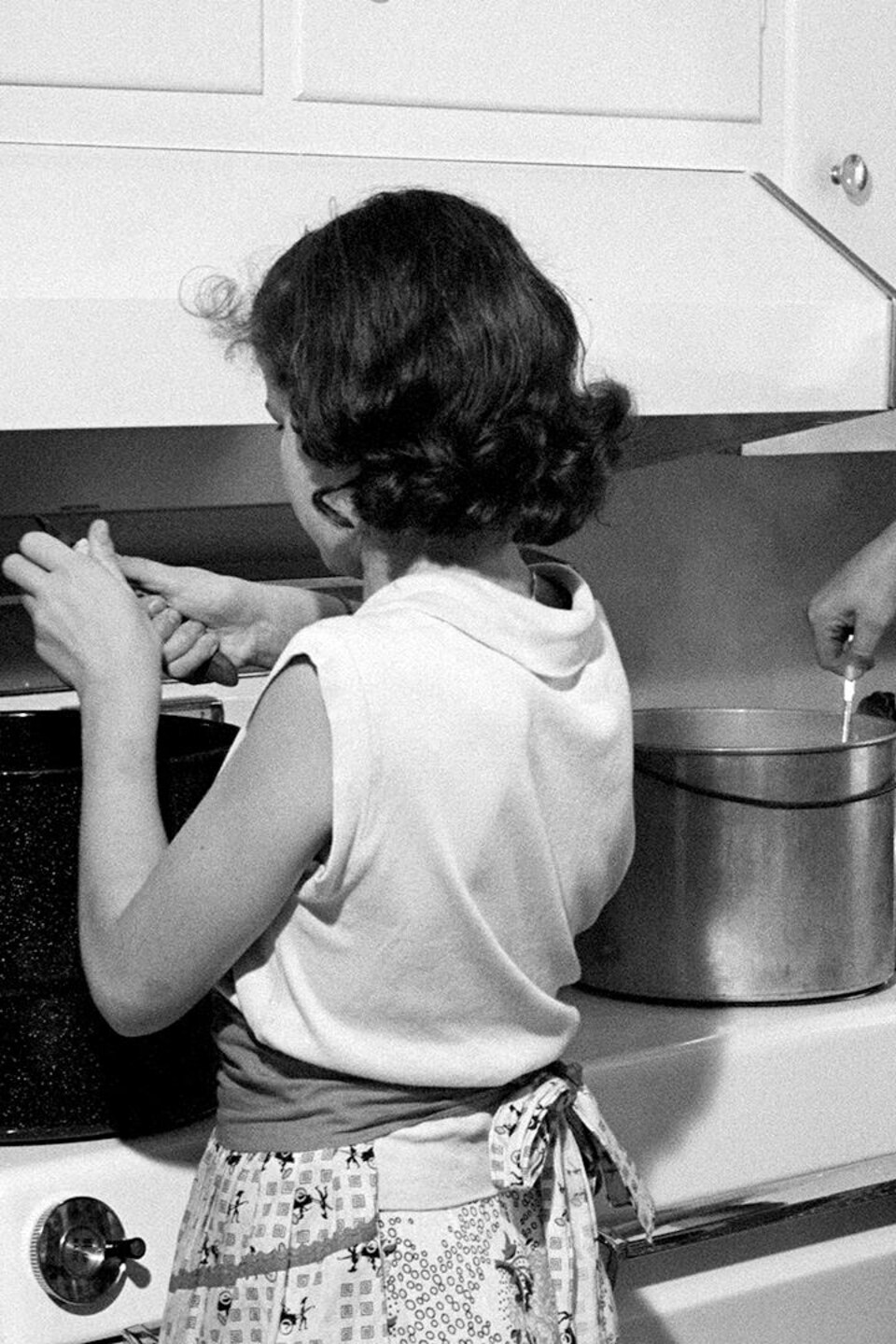 Une mère et sa fille qui cuisinent devant les chaudrons sur la cuisinière.