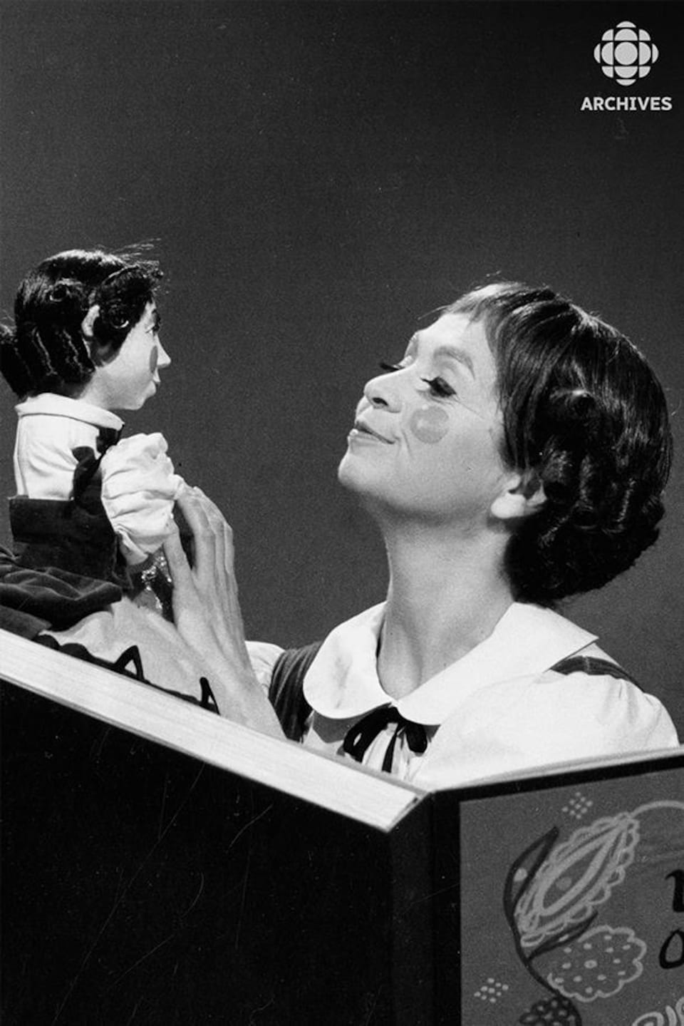 Fanfreluche (Kim Yaroshevskaya) derrière son grand livre, en compagnie d'une marionnette à son image.