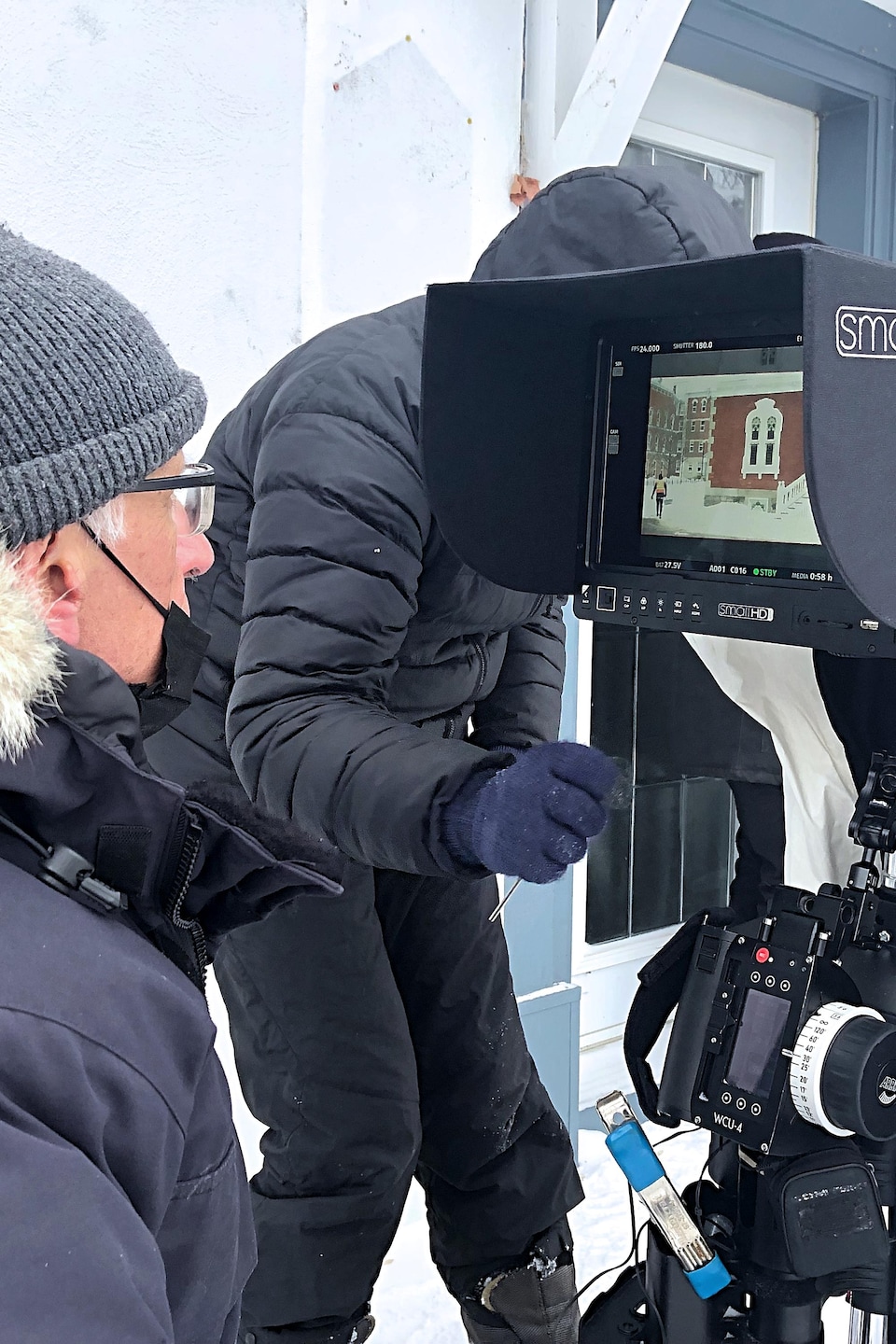 Assis à l’extérieur avec son manteau d’hiver, le réalisateur du film, Bernard Émond, regarde à travers une caméra l’image de la maison de son personnage principal.