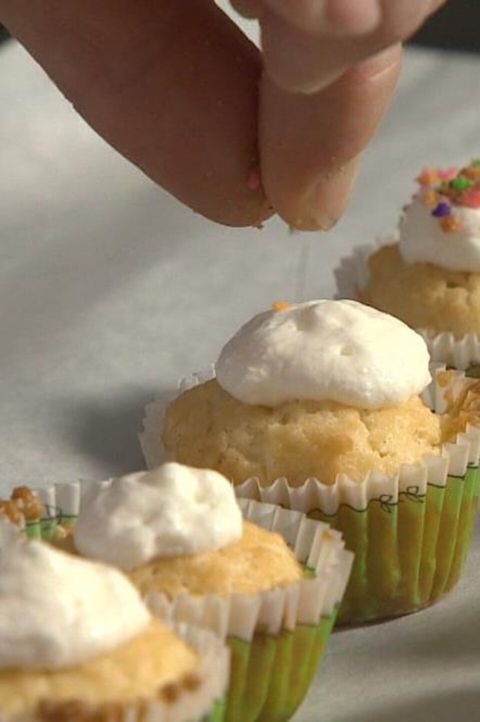 Un cuisinier met un glaçage à la vanille sur ses petits gâteaux.