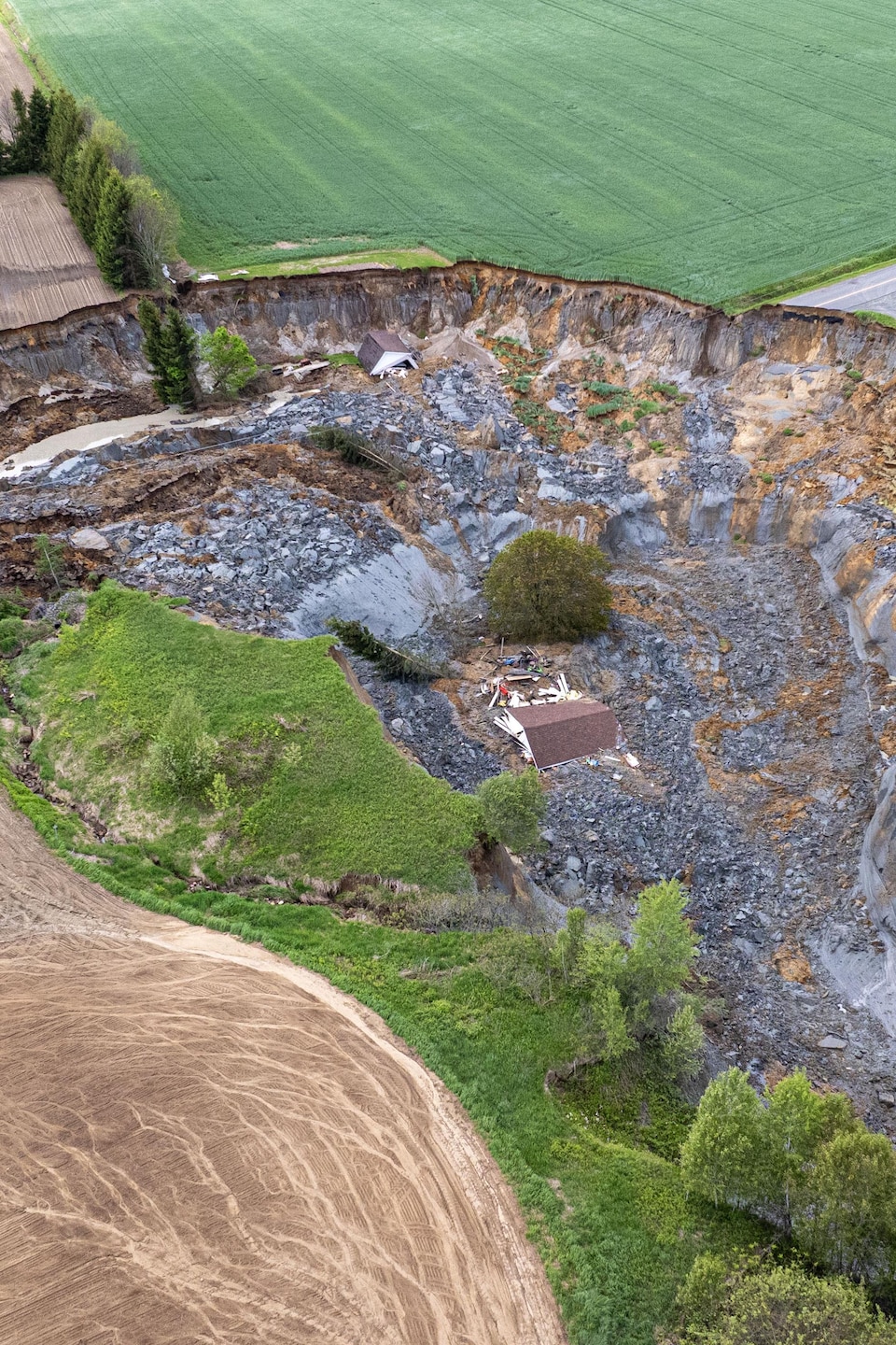 Une image aérienne d'une maison dans un cratère de boue.