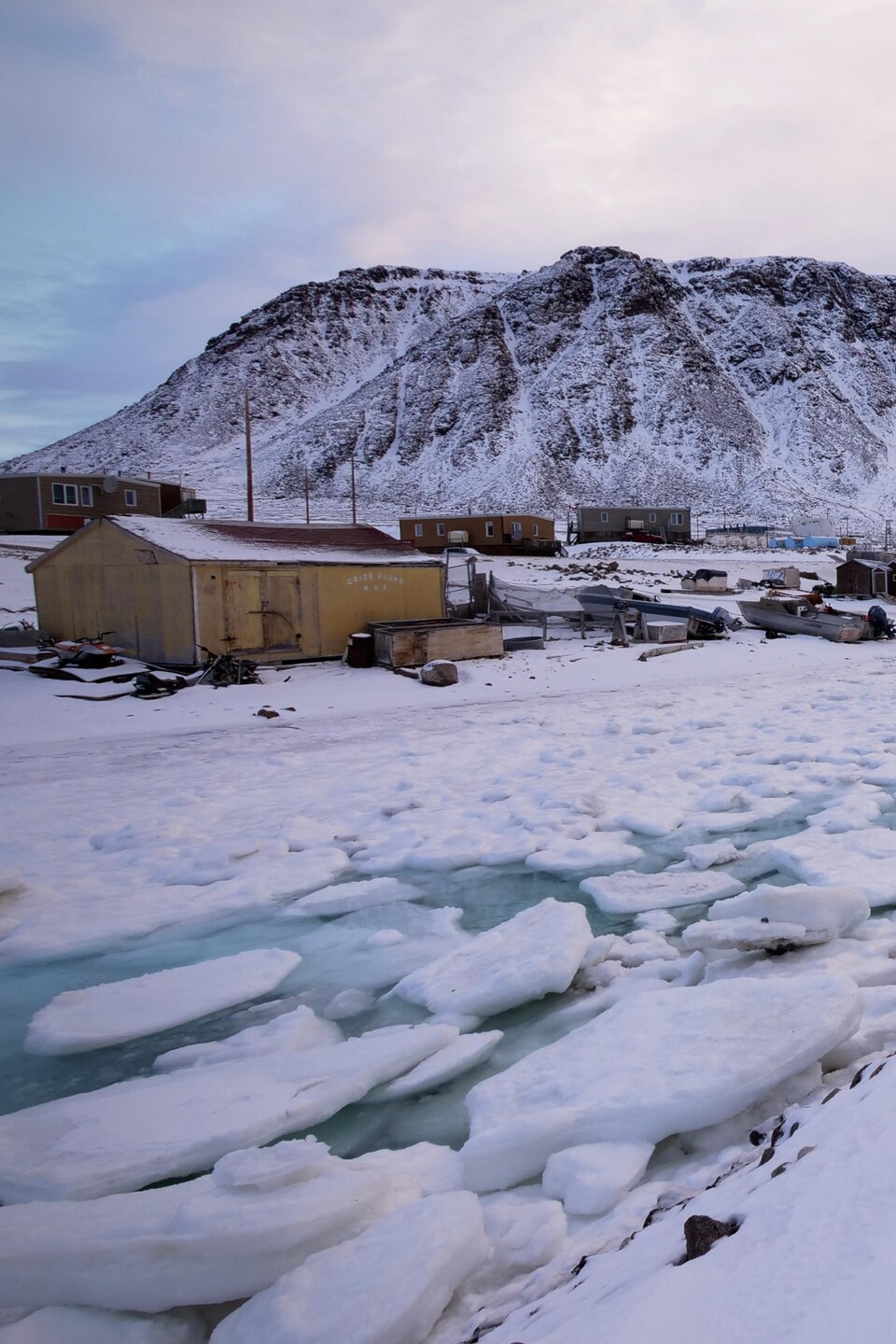 Des habitations nichées dans les glaciers sur le bord d'une voie d'eau glacée.