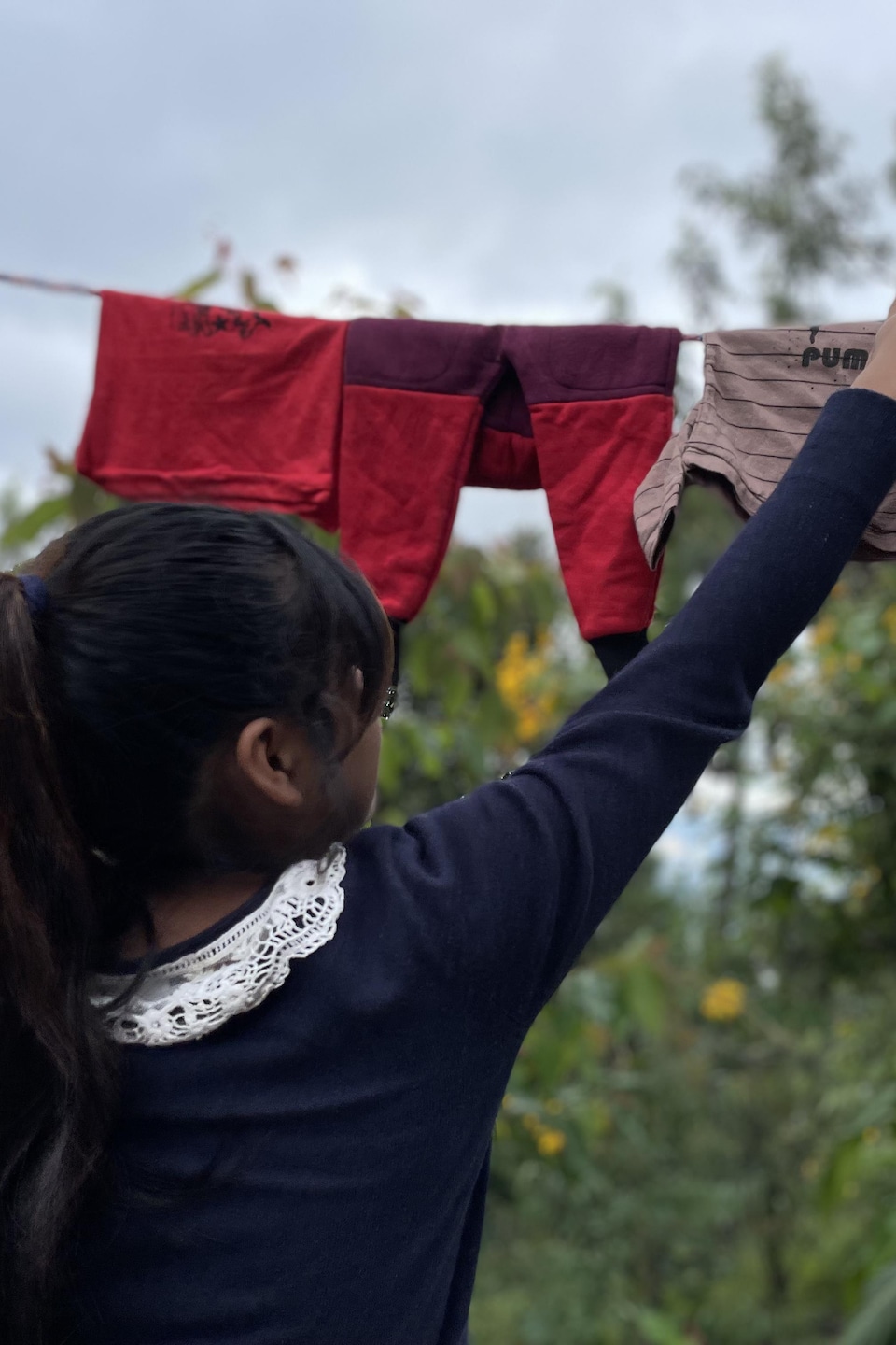 Une adolescente accroche des vêtements de bébé sur une corde à linge.