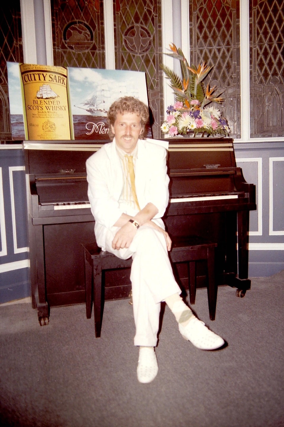 Un homme est assis sur un banc de piano devant l'instrument.