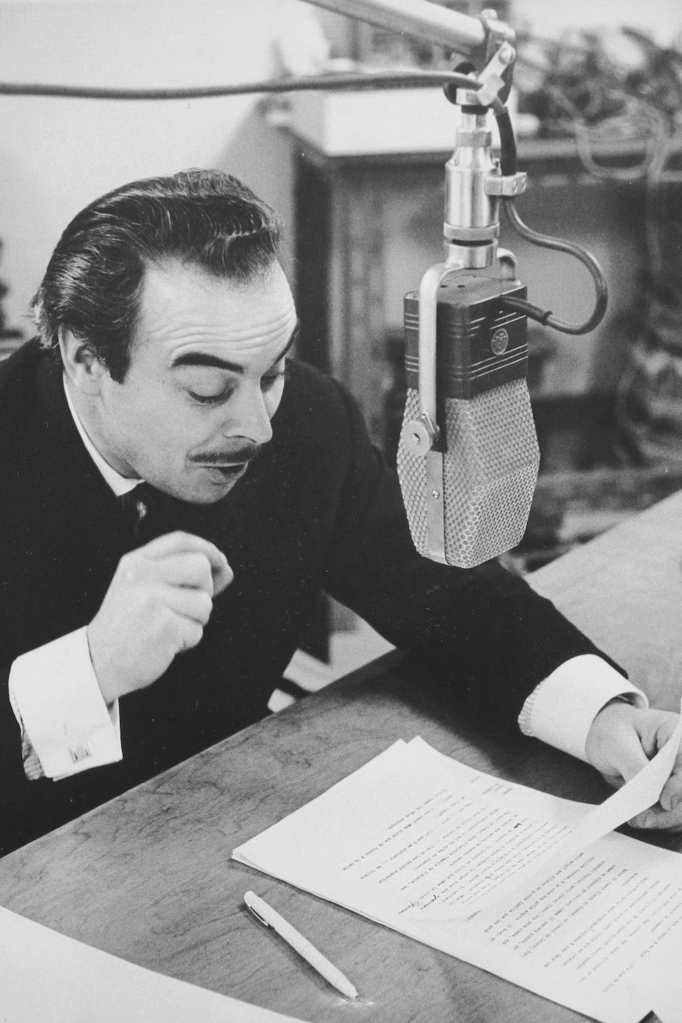 Henri Bergeron lit un conte dans un studio radio avec un visage particulièrement expressif.