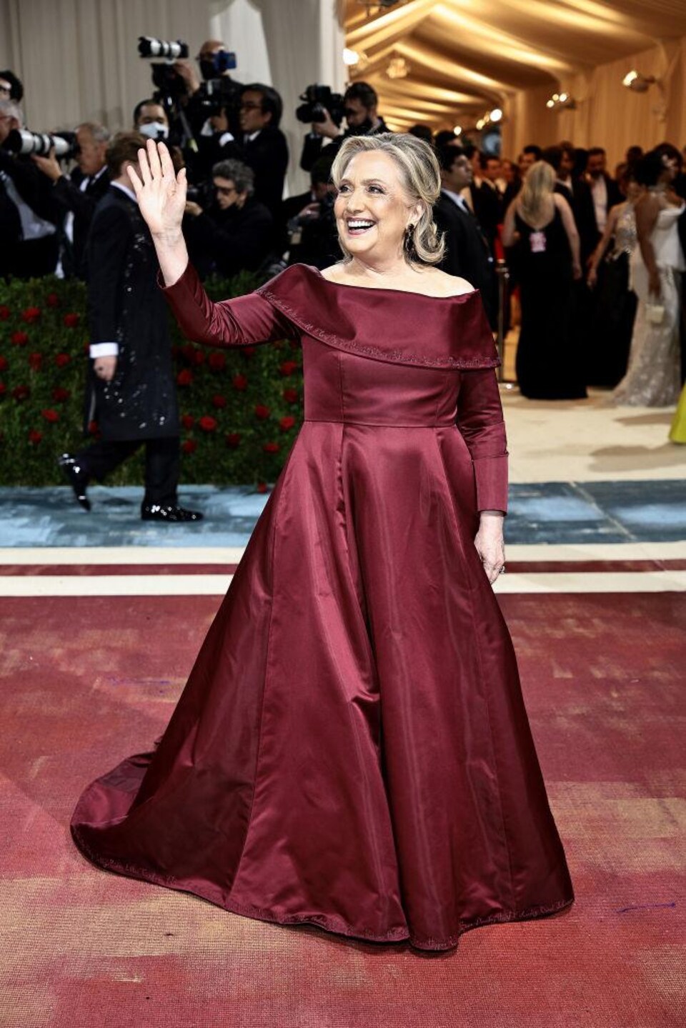 A woman is wearing a long burgundy dress.