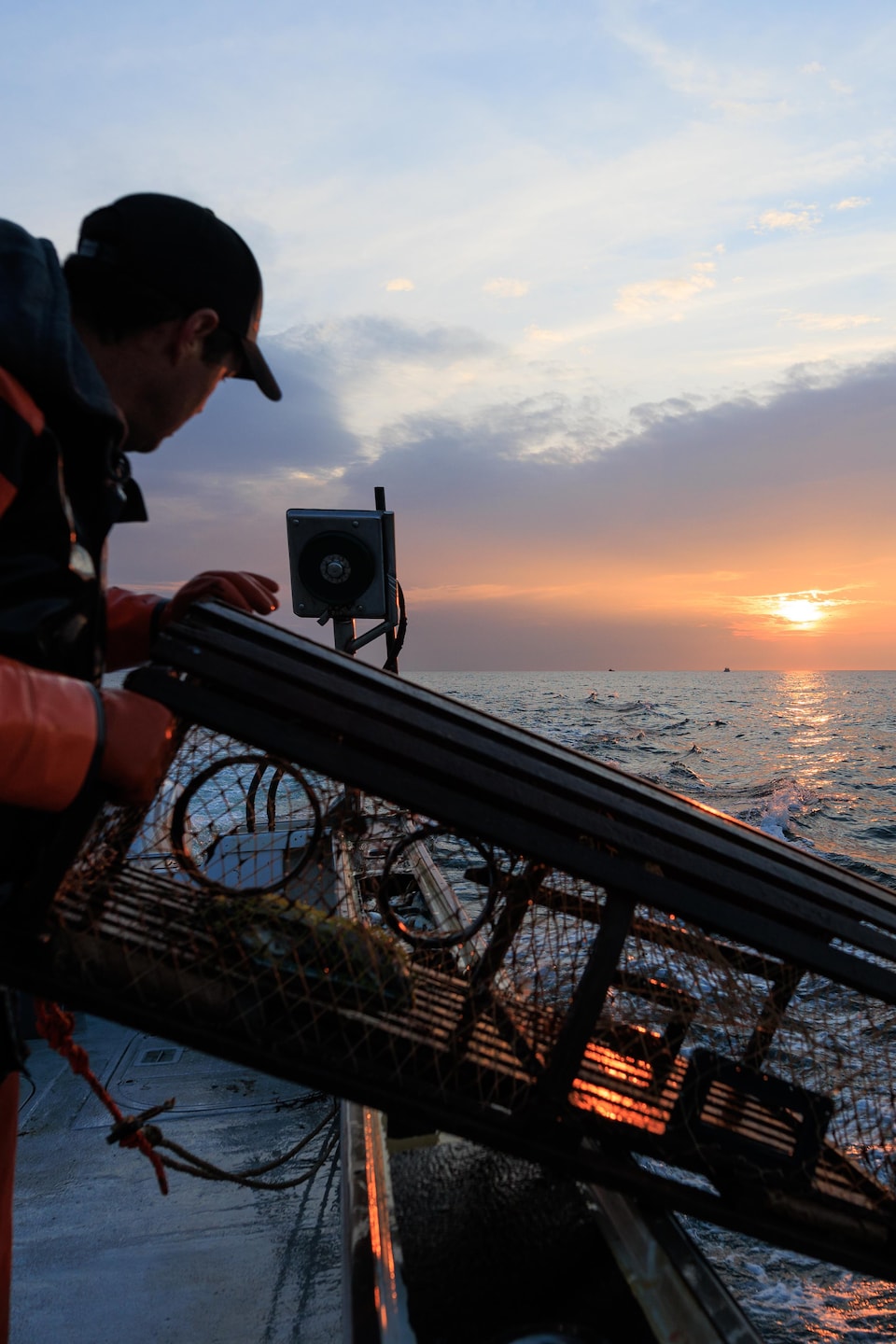 Un homme pousse une trappe à homard alors que le soleil se lève.