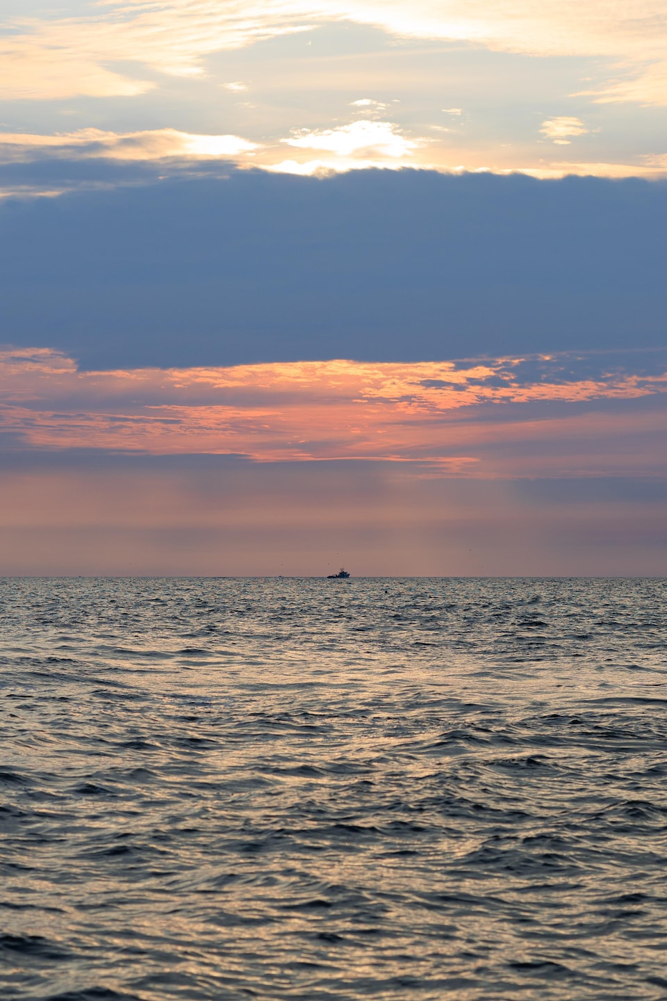 Un bateau au loin alors que le soleil se lève.