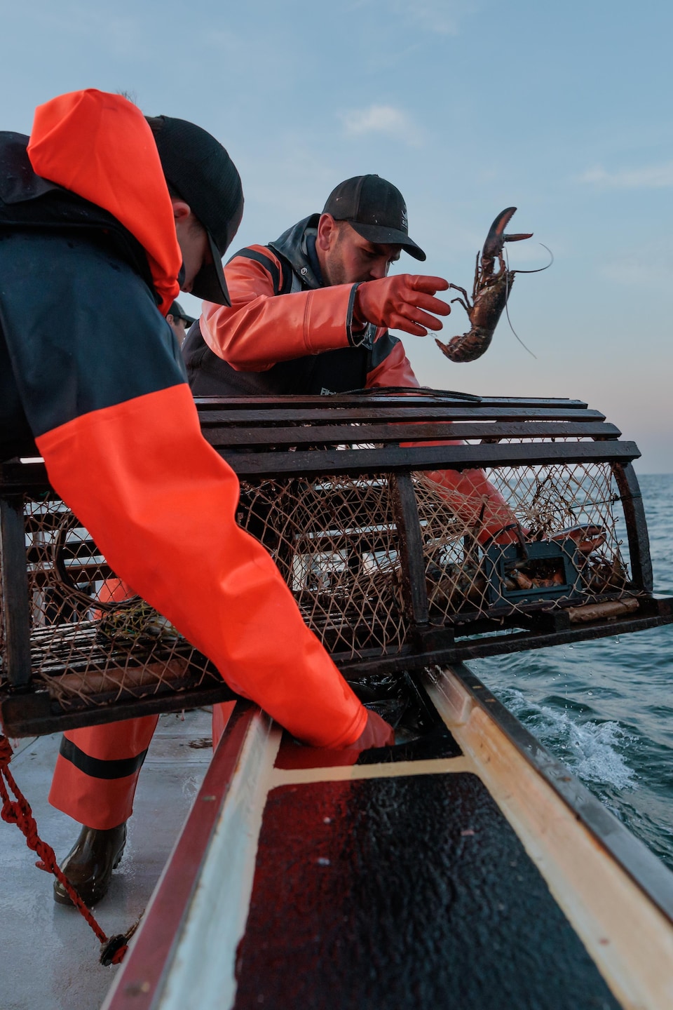 Deux hommes travaillent sur bateau en mer.