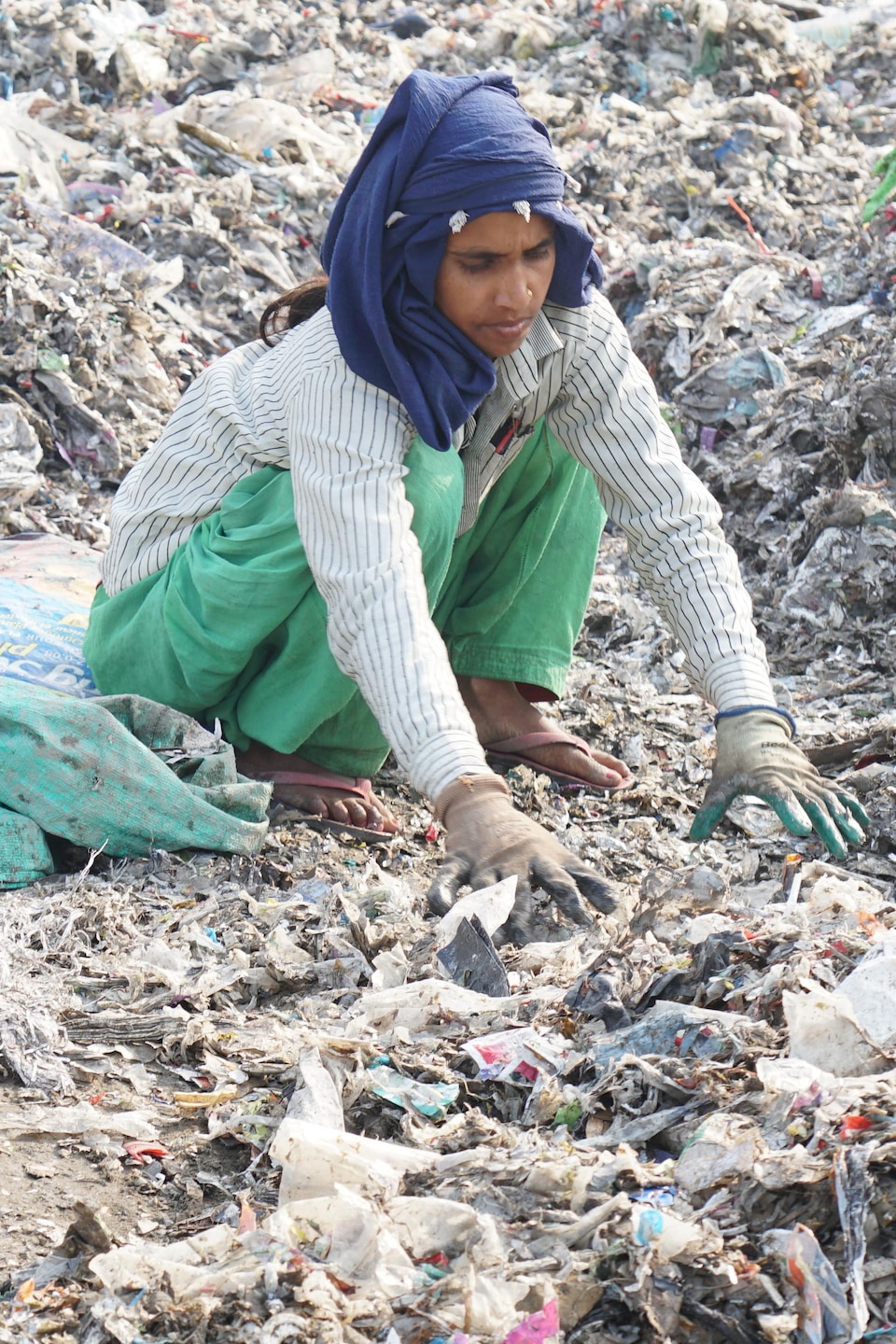 Une femme accroupie sur des déchets.