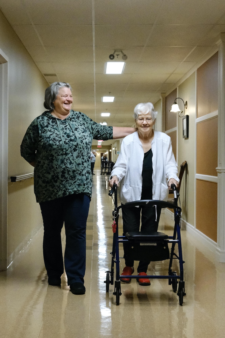 Isabelle Morasse et Rollande Camirand-Morasse marchent dans un couloir d'une résidence pour aînés.
