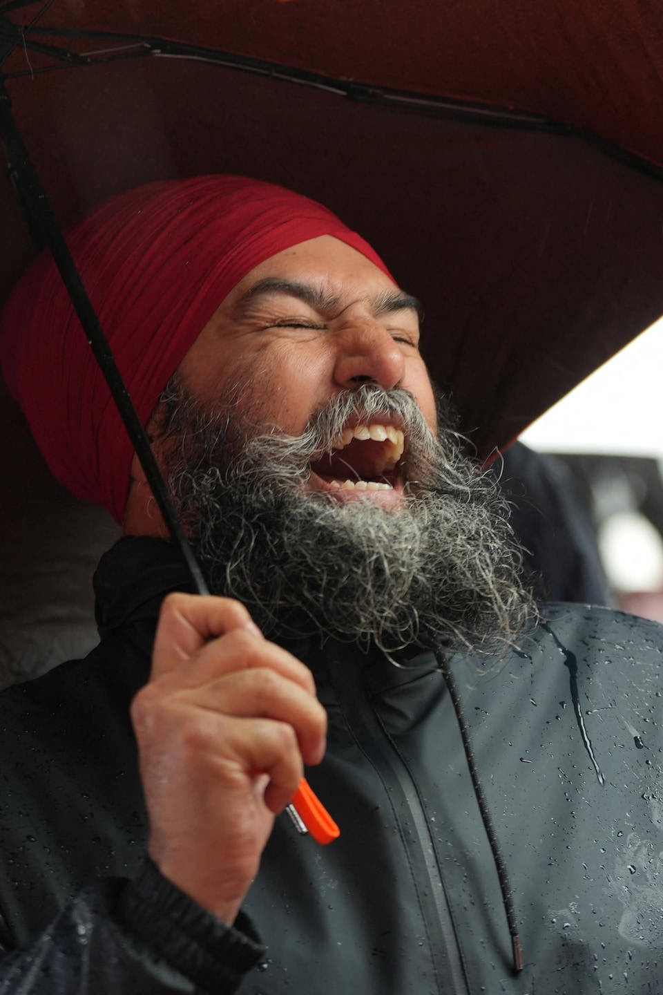Jagmeet Singh rit aux éclats sous un parapluie.