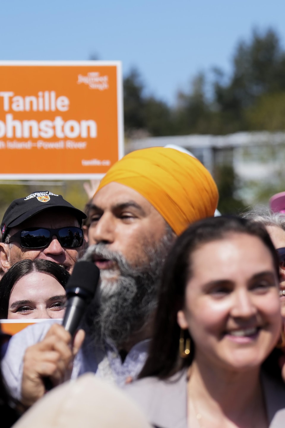 Jagmeet Singh dans une foule où une femme soulève lad   petit chien au-dessus de tout le monde.