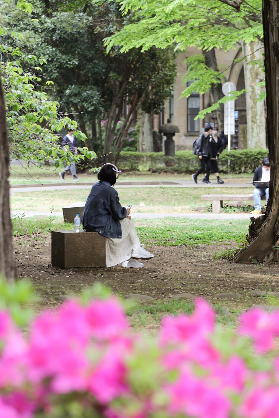 Une femme assise seule dans un parc avec des écouteurs.