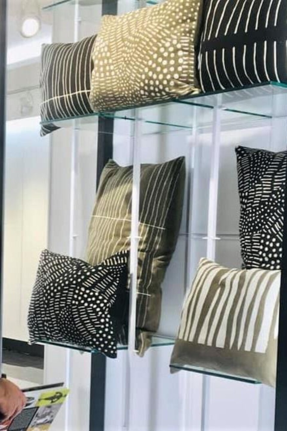 Des coussins sont exposés sur des étagères en verre.