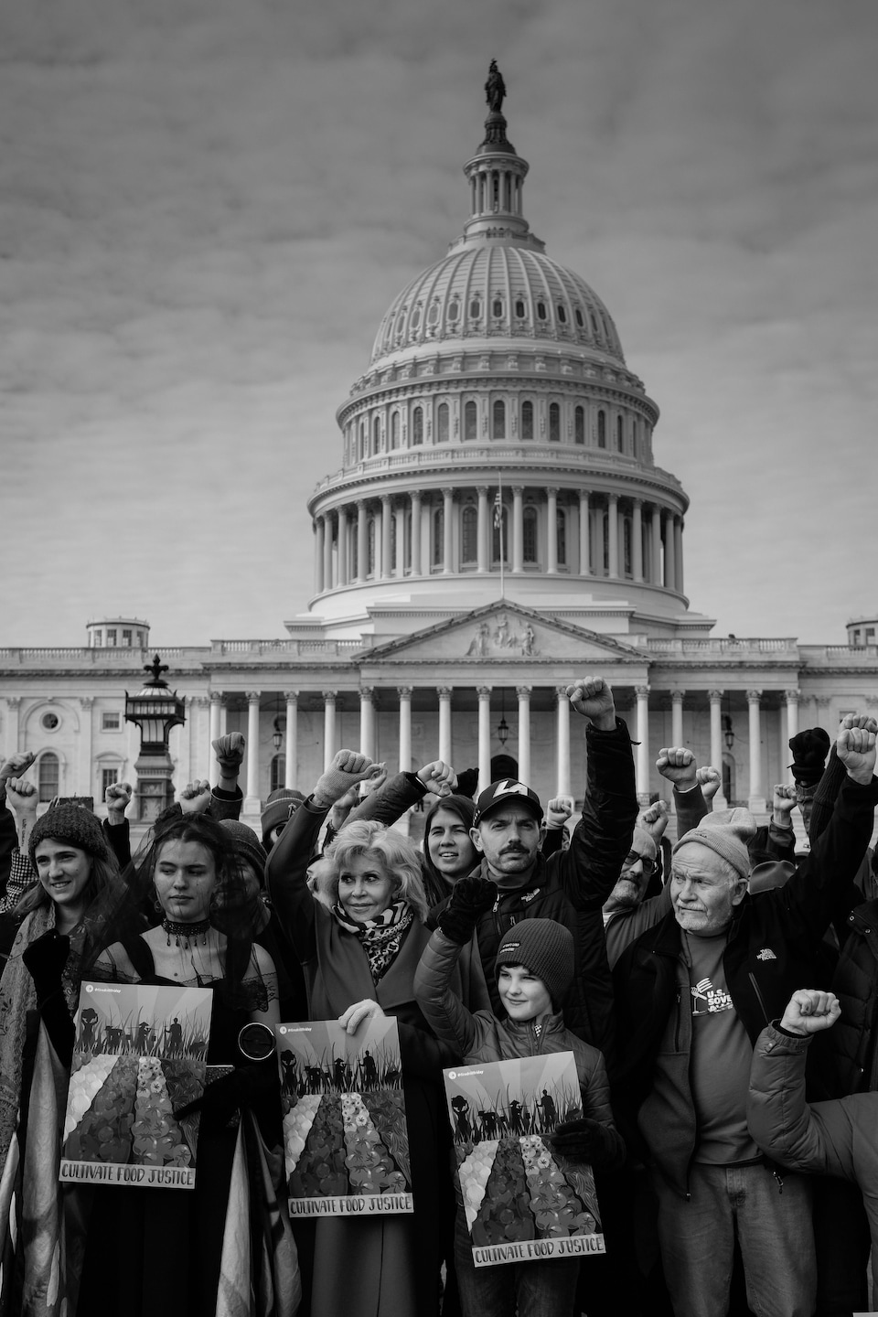 Protesters are holding signs outside the United States Capitol in Washington, in a black and white photo.