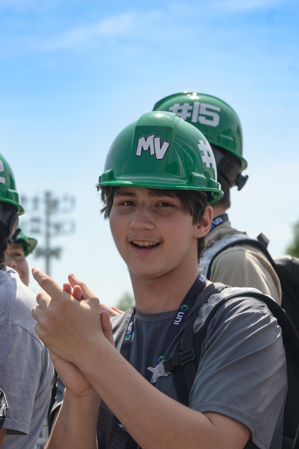 Un jeune applaudit avec un casque de operation  vert sur la tête.