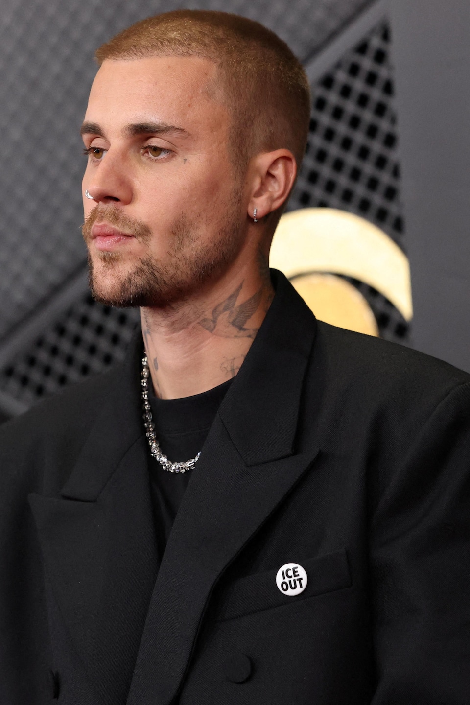 Justin Bieber pose sur le tapis rouge, arborant un badge « ICE OUT ».