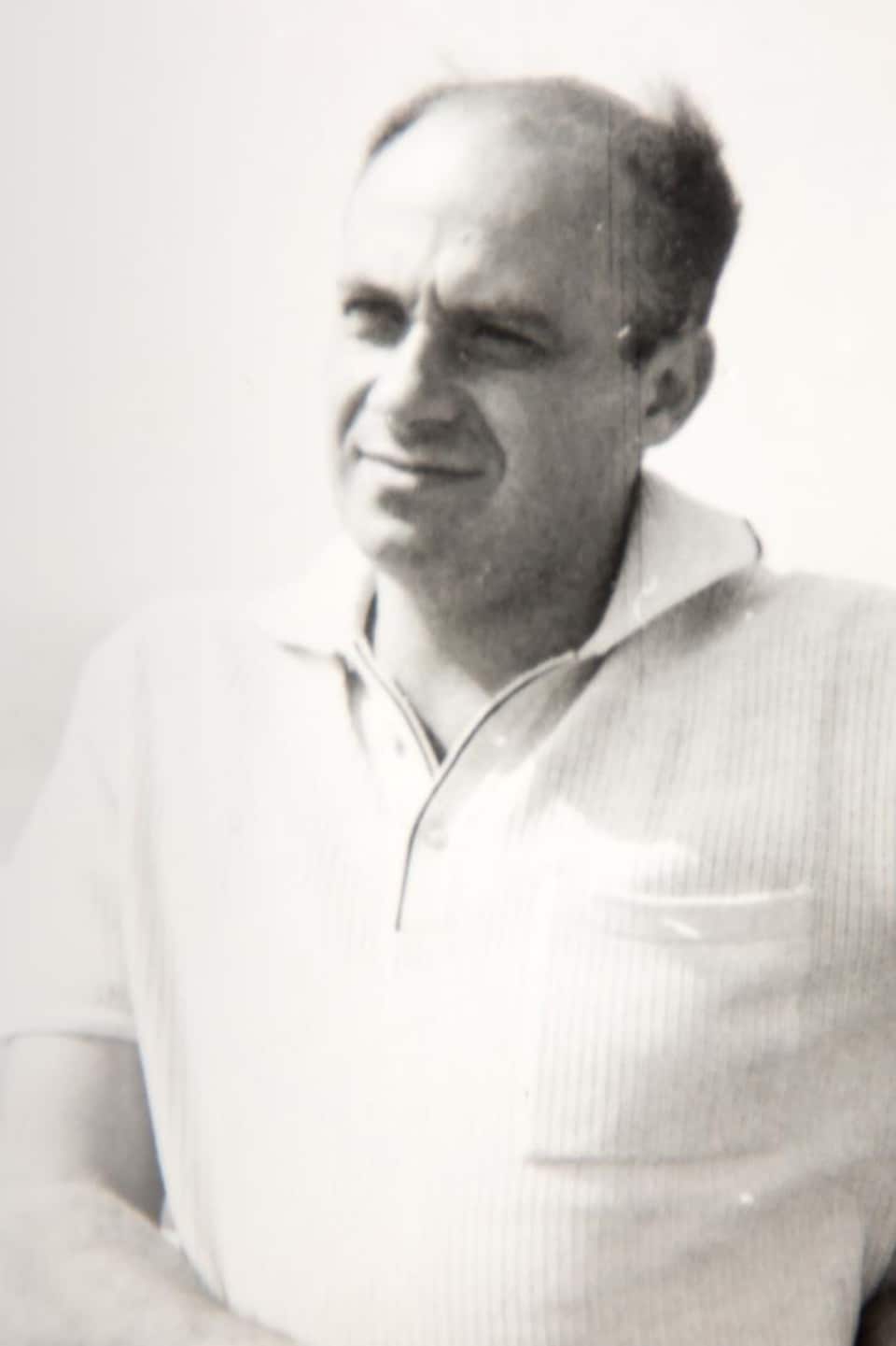Portrait de George Kellner en noir et blanc, où il regarde à l'horizon avec une main sur la hanche.