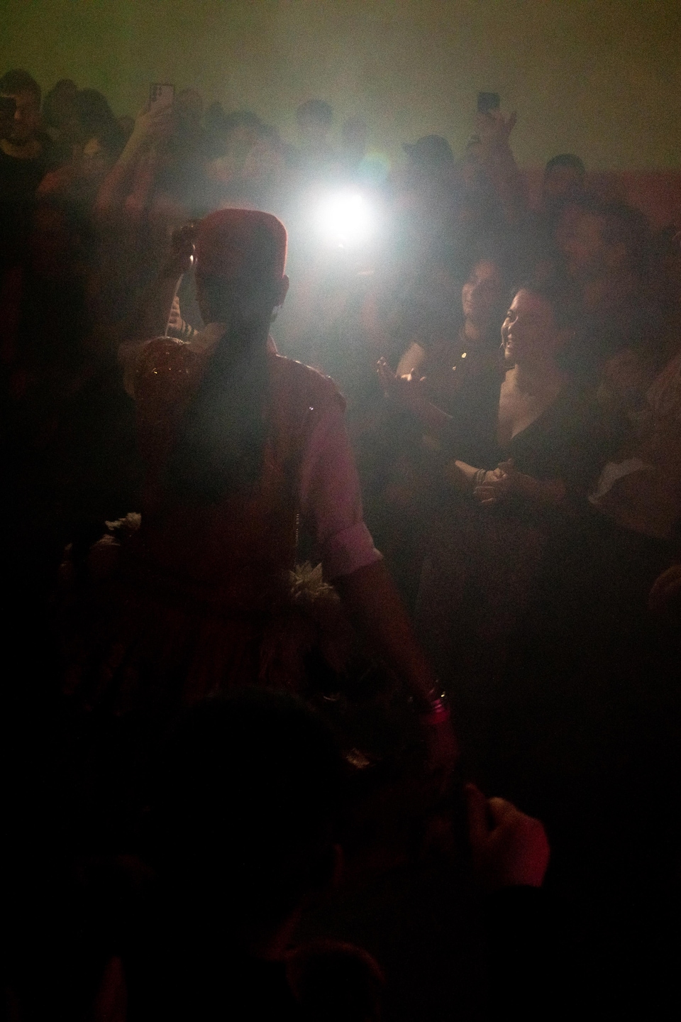 Une personne tenant un téléphone éclaire la silhouette d'Achraf, qui danse.