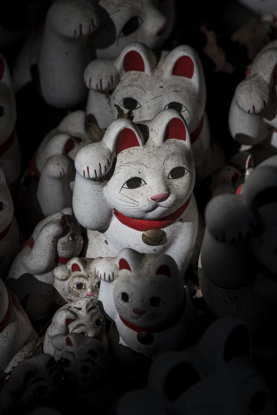 De multiples sculptures de chats dans un temple au Japon.