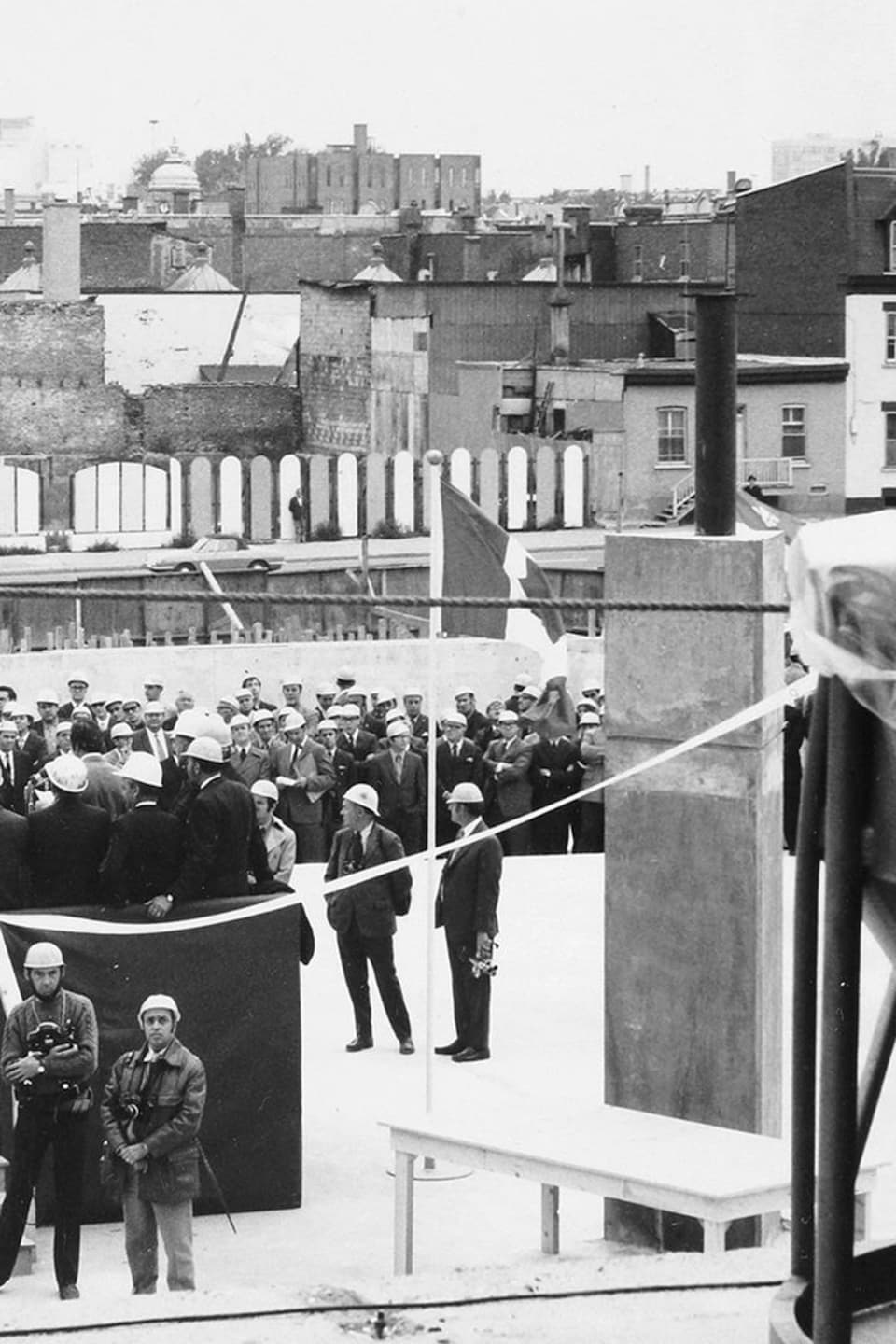 Plusieurs personnes portant des casque de protection rassemblées sur le chantier de construction de la Maison de Radio-Canada. 