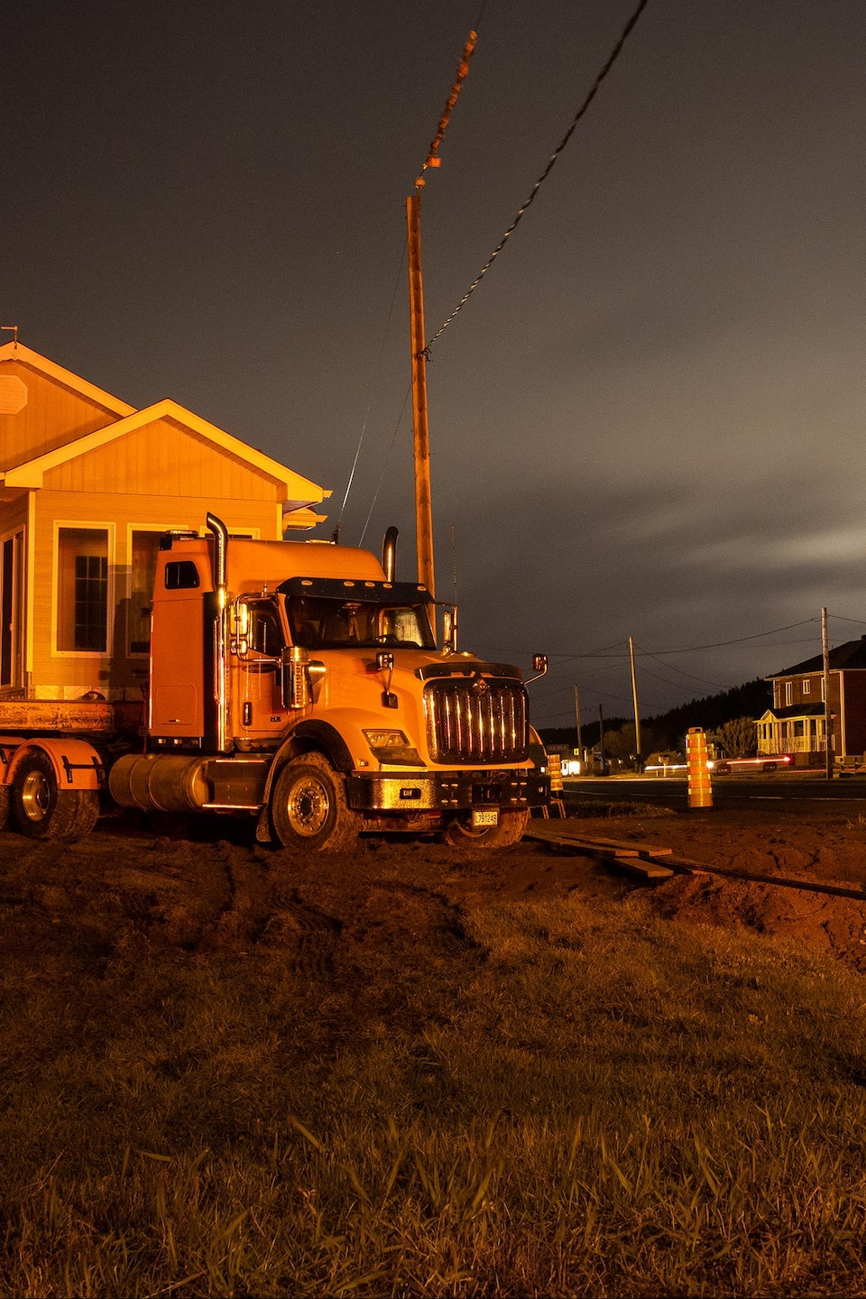 Une maison déposée sur un camion-remorque doit être déplacée de l'autre côté d'une route en pleine nuit.