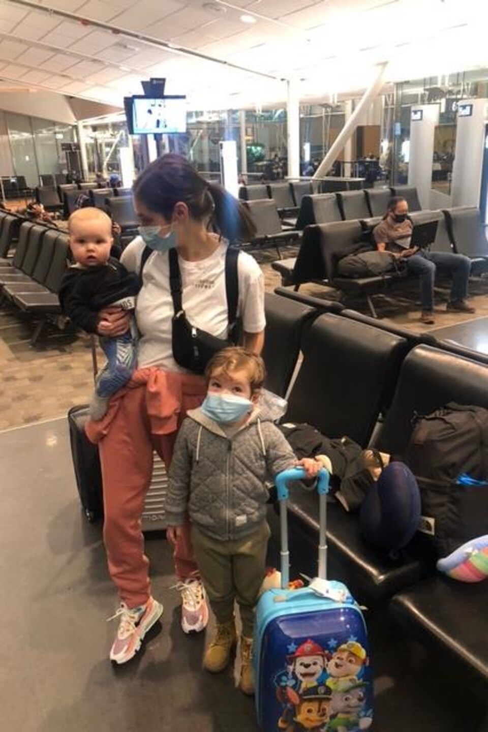 Une mère avec ses deux enfants à l'aéroport.