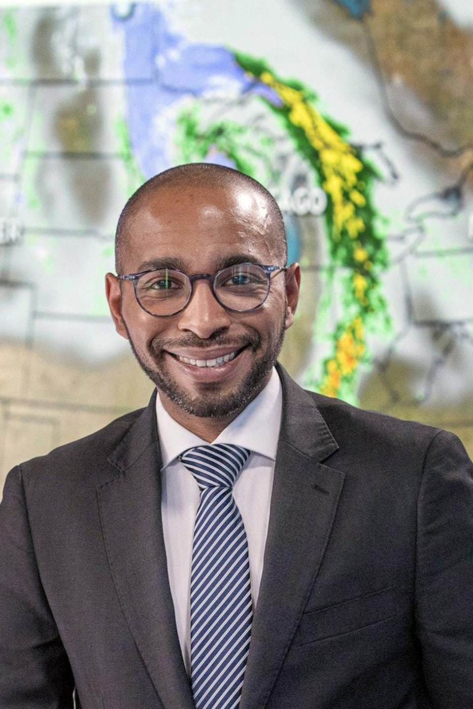 Waldir DeCruz souriant devant une carte météo. 