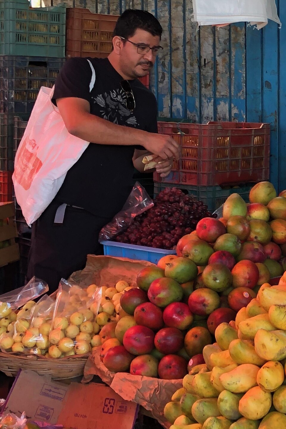 Rodolfo Castellanos devant des étals de fruits et légumes.