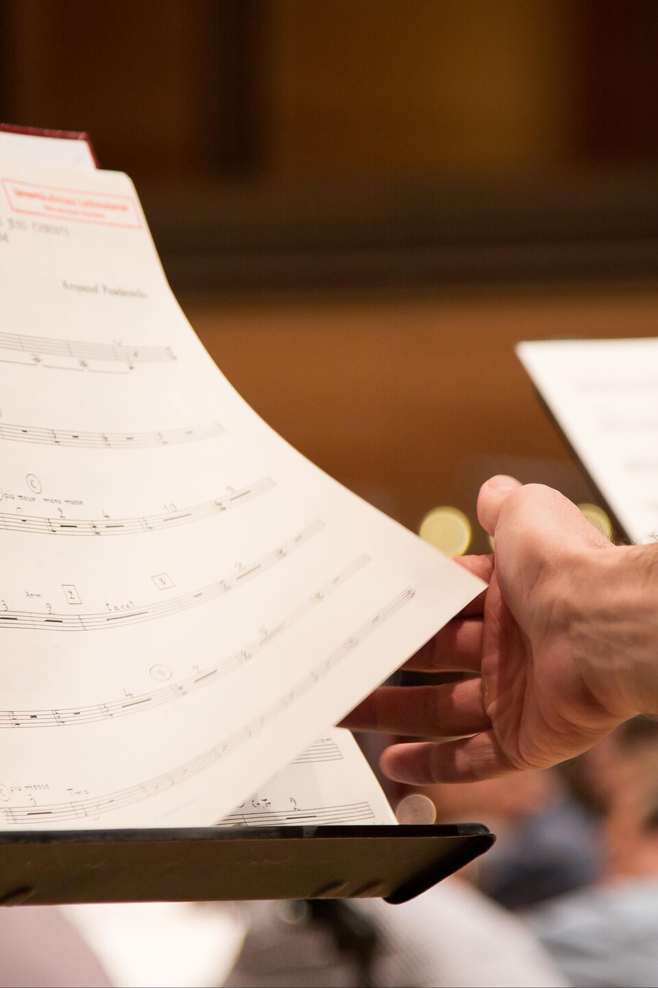 La main d'un musicien tourne une page de sa partition, pendant une répétition de l'Orchestre Symphonique de Montréal.