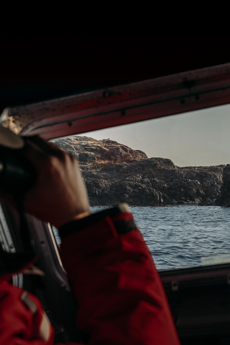 Thomas Doniol-Valcroze de dos, en train de regarder avec des jumelles le récif par le hublot d'un bateau, à Nanaimo, en Colombie-Britannique, en octobre 2022.