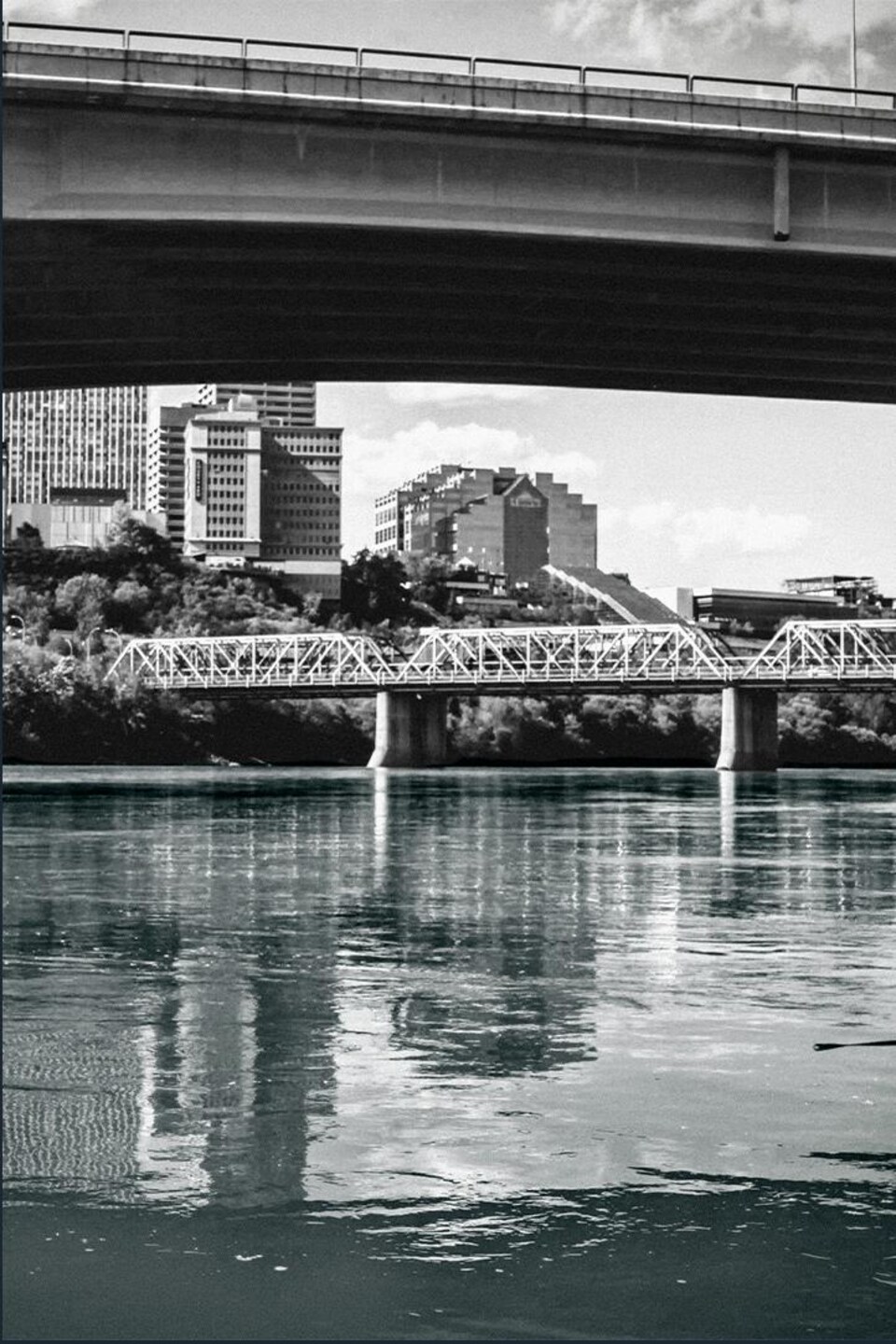 La rivière sous les ponts. Des bâtiments urbains et des tours s'élèvent sur les falaises en arrière-plan.