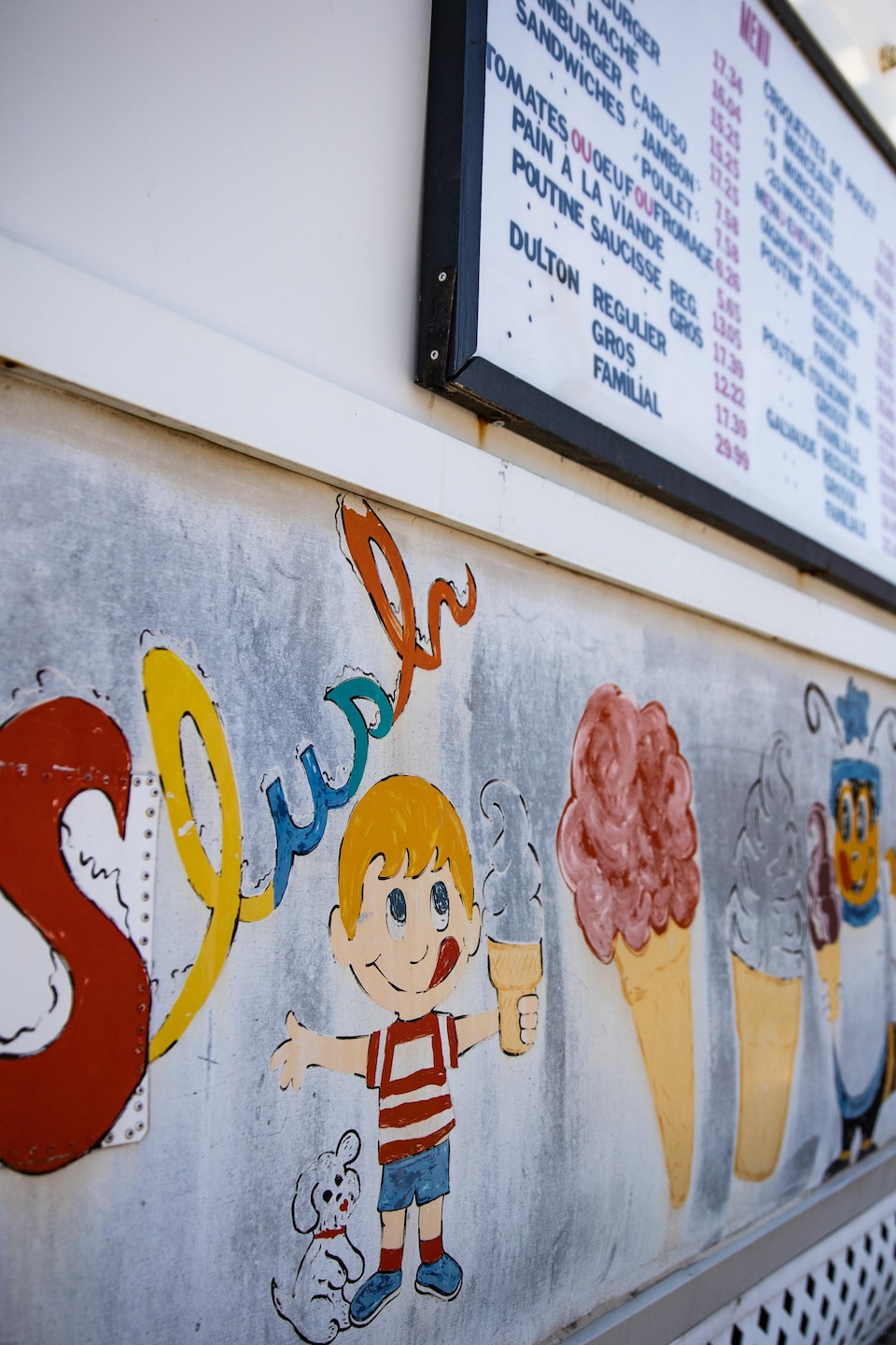 Une murale peinte du mot « Slush » et de friandises illustre le bâtiment d'un commerce où attendent deux clientes.