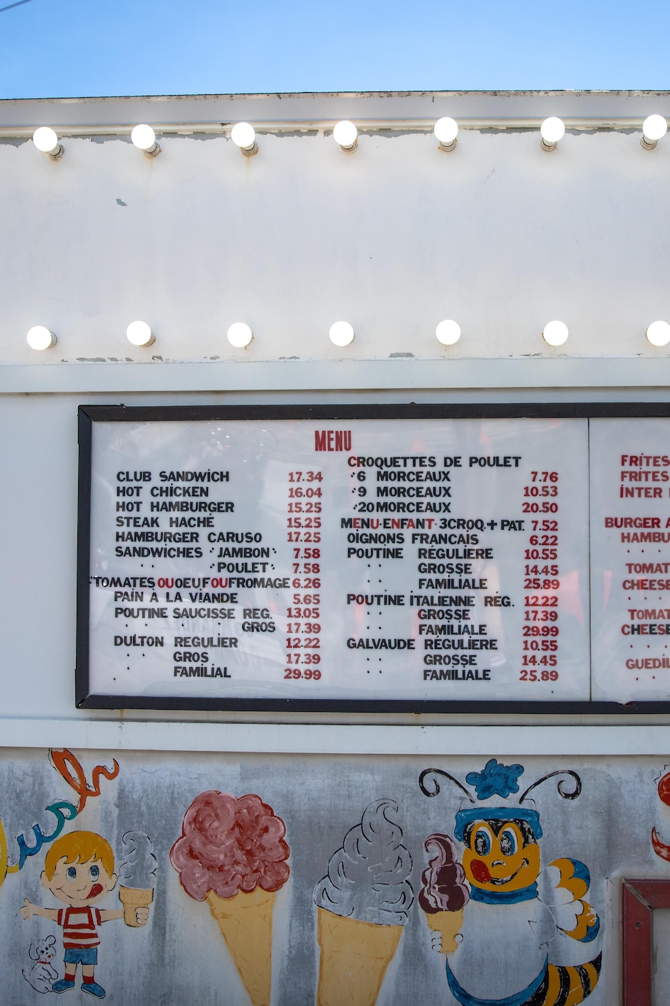 Un panneau d'affichage du menu et des prix est accroché sur le mur extérieur décoré d'une cantine.