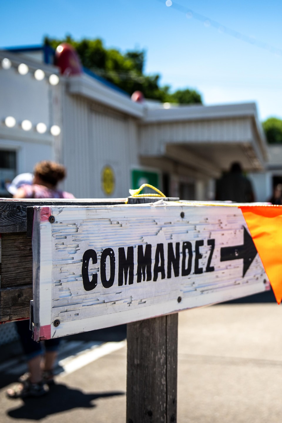 Un panneau en bois portant la mention « Commandez » indique la direction à suivre sur le stationnement de la cantine Chez Micheline.