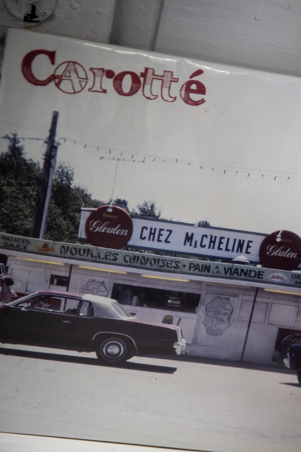 Une main pointe l'enseigne de la cantine Chez Micheline sur une pochette d'album de Carotté.