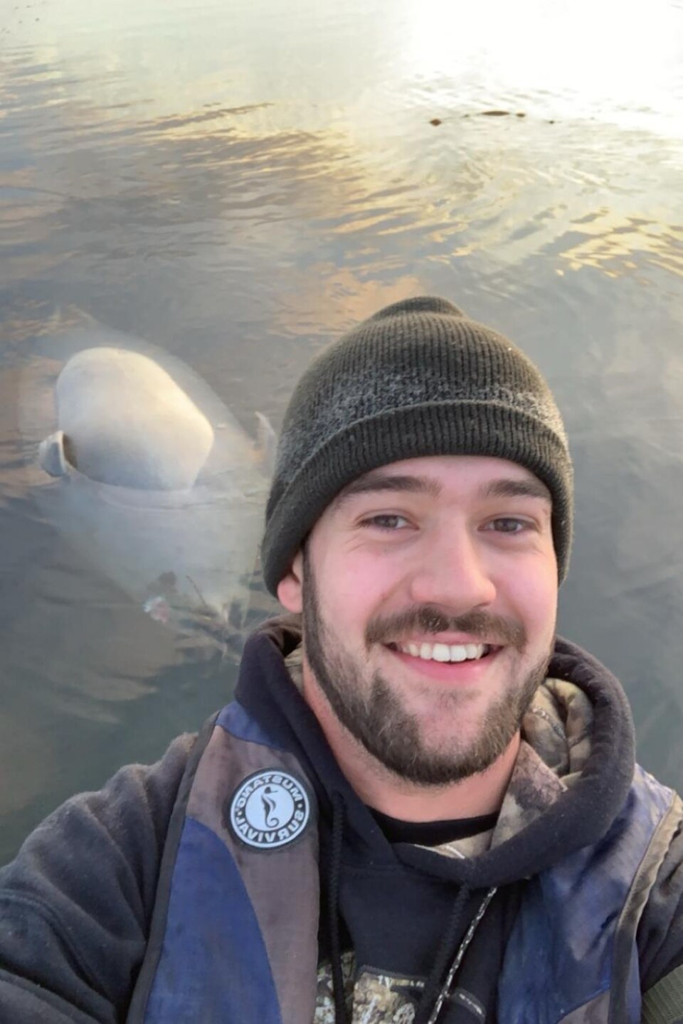 Pier-Olivier Leblanc sourit à la caméra. Derrière lui, une carcasse de phoque flotte à la surface de l'eau.