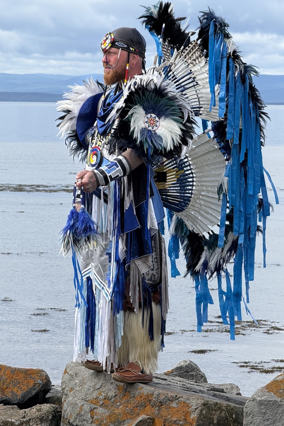 Un homme en tenue traditionnelle devant le fleuve.