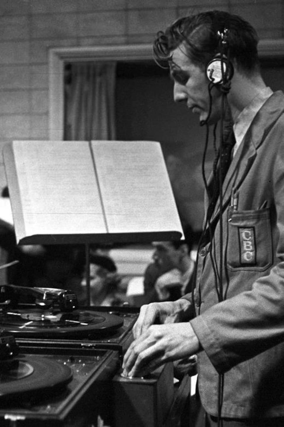 Dans un studio de radio, le technicien Albert Deamen, insère les portions musicales durant la diffusion de l'émission.