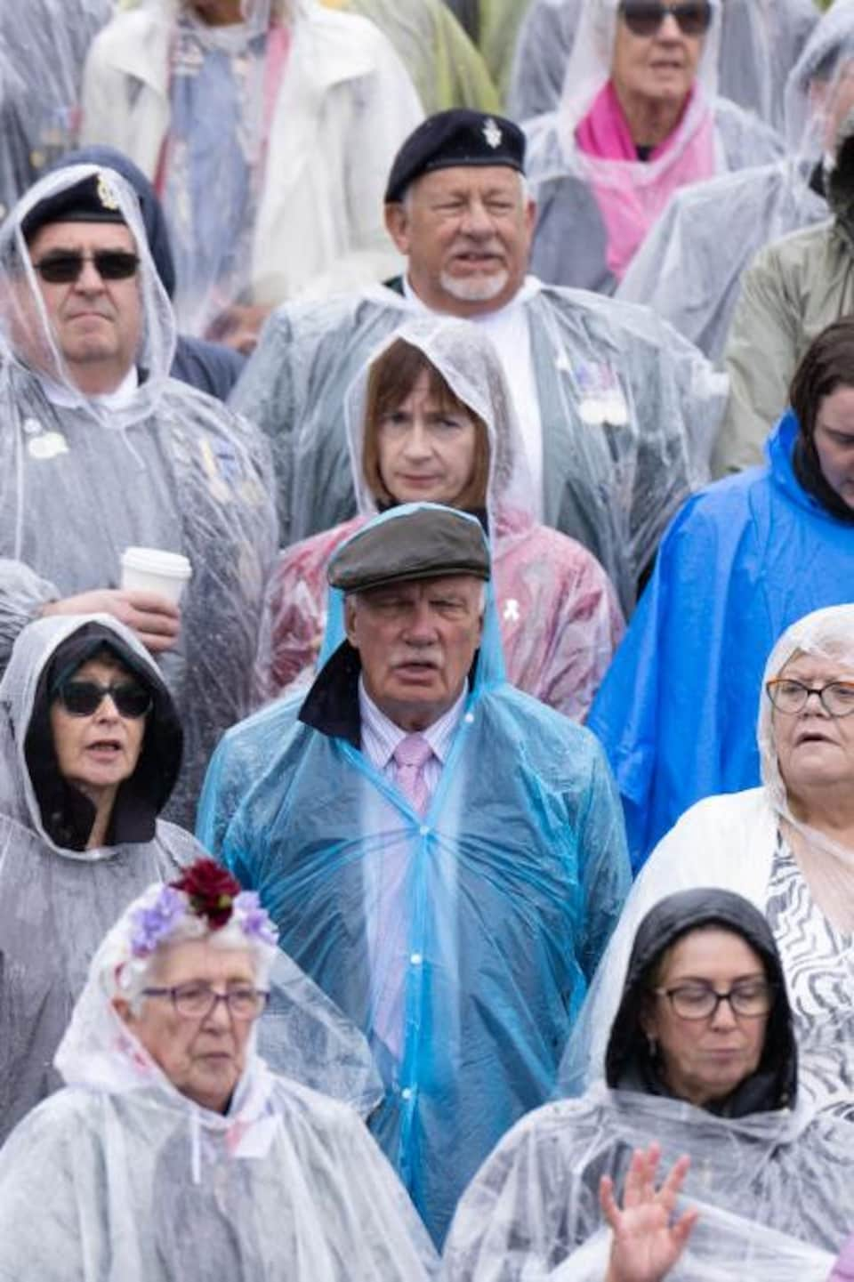 Des gens portent des ponchos de plastique sous la pluie.