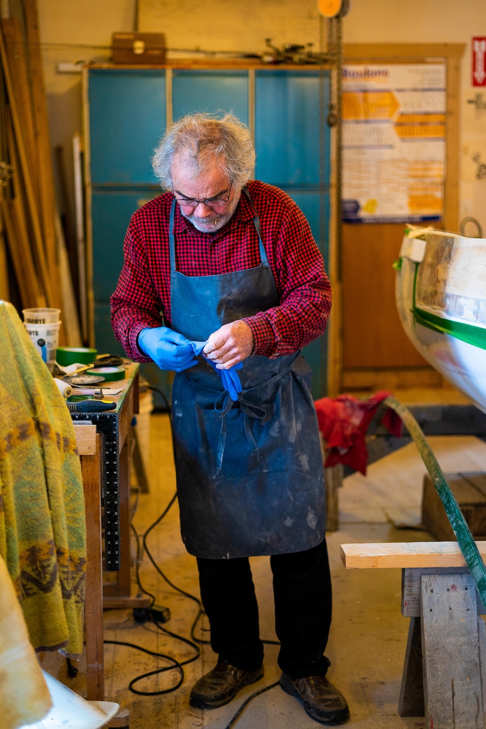 Daniel St-Pierre est debout dans son atelier et enfile des gants.