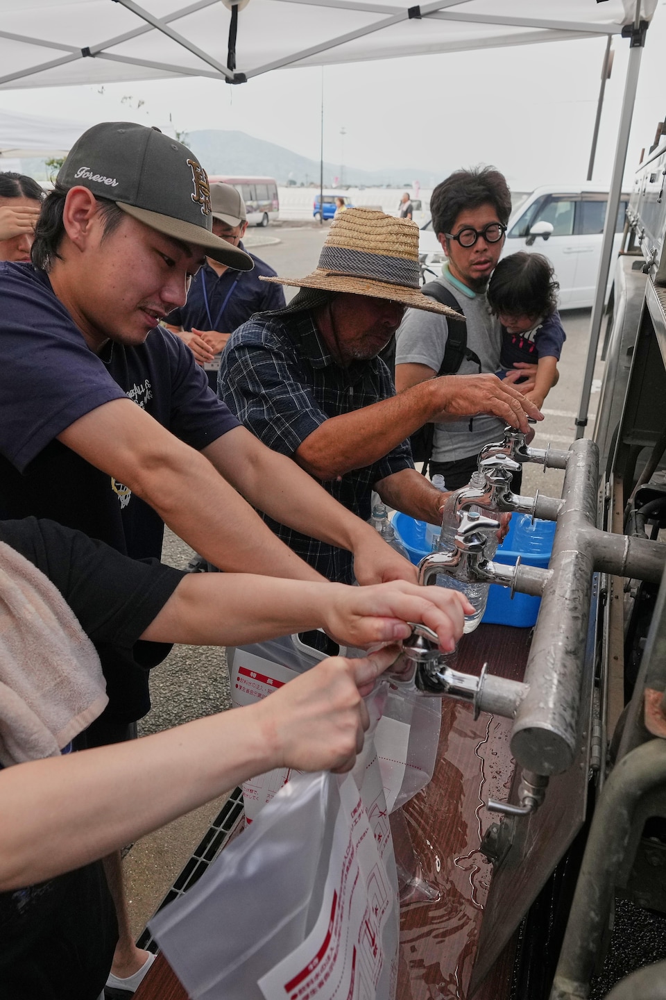 Des personnes remplissent des sacs avec de l'eau potable contenue dans un camion-citerne.