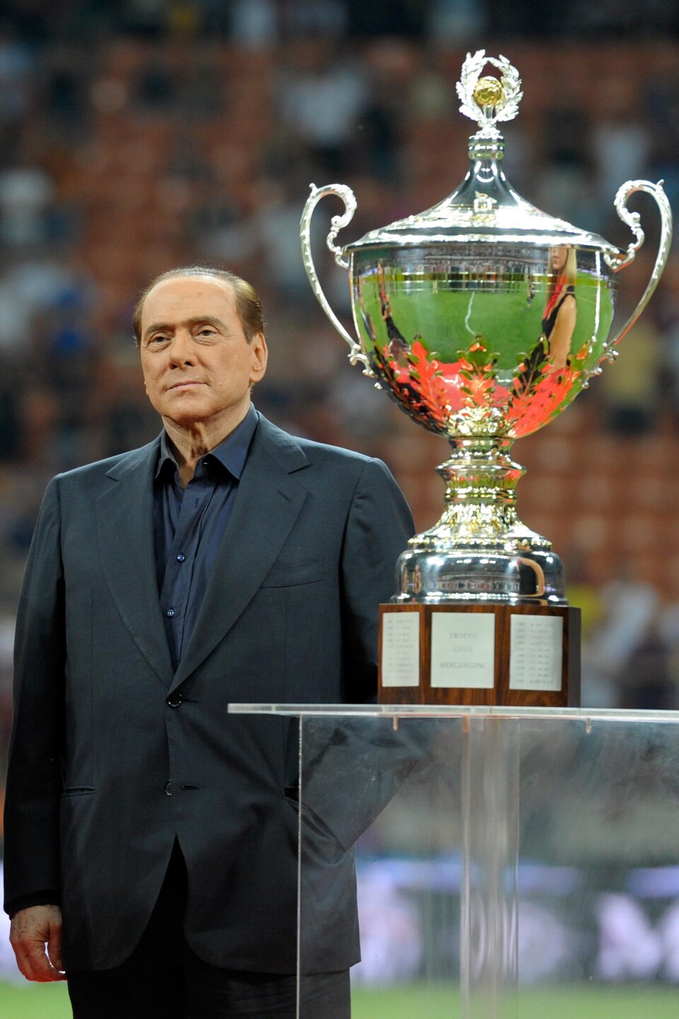 Silvio Berlusconi stands behind the trophy.