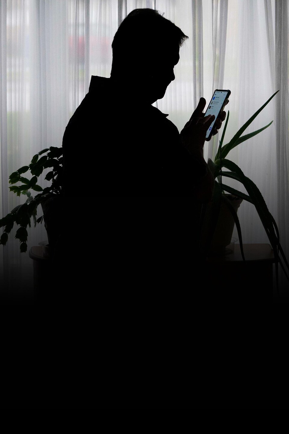 La silhouette d'une personne qui consulte son cellulaire.